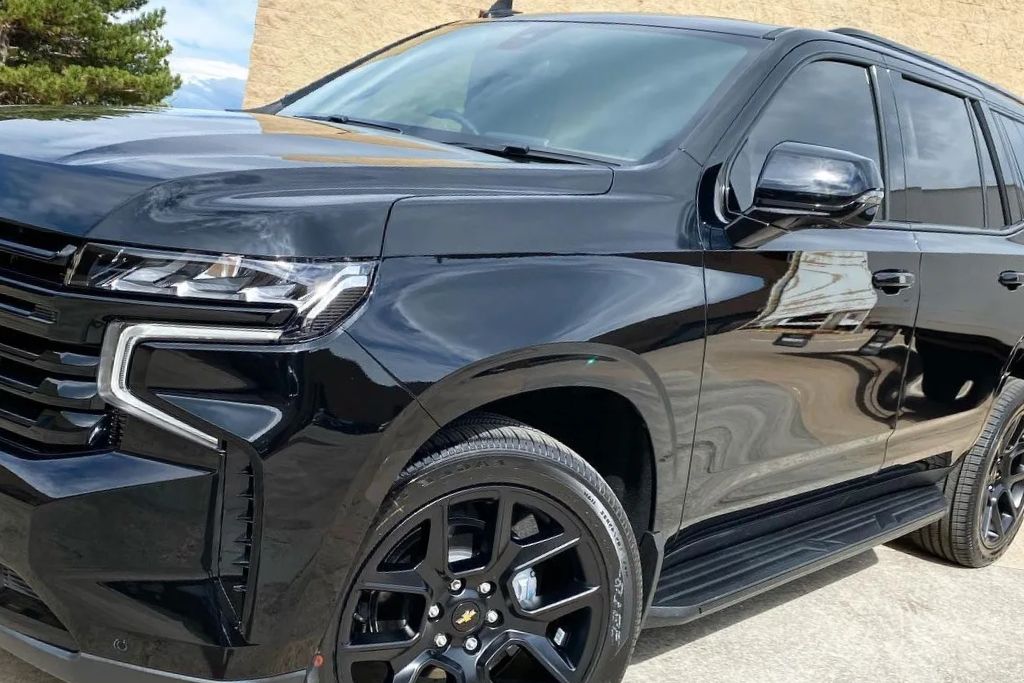 A black Chevy Tahoe with glossy paint and dark ceramic window tint reflecting the surrounding environment. The high-quality tint enhances privacy, reduces glare, and provides superior heat rejection. The SUV’s bold design and tinted windows highlight the premium benefits of ceramic window tinting.