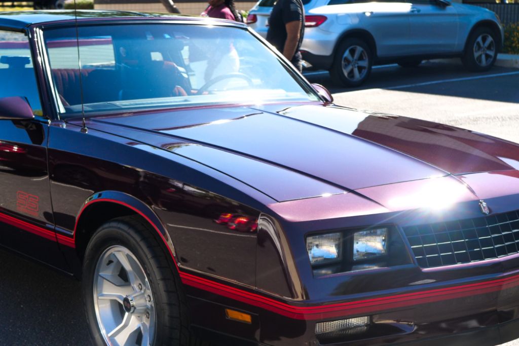 Glossy classic car parked in sunlight, illustrating the role of car window tint in blocking UV rays and protecting both the interior and occupants.