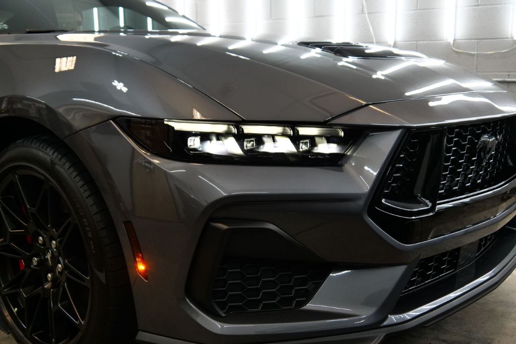 Close-up of a sleek gray sports car front end with glossy, flawless paint, representing a well-protected finish and illustrating steps in how to protect new car paint.