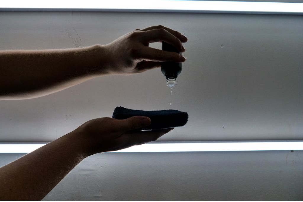 A technician in Surprise, AZ at 48 Detailing applies a few drops of ceramic coating solution onto an applicator pad, visually representing the science behind ceramic coating and its precise, professional application process.