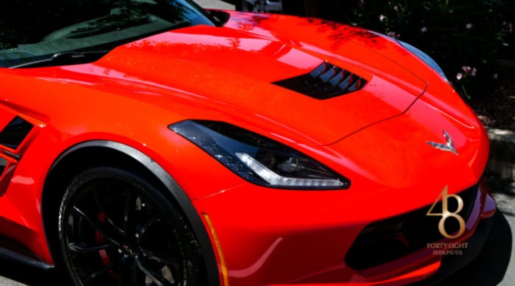 Glossy red sports car with ceramic-coated paint protection film reflecting sunlight, professionally detailed by 48 Detailing.