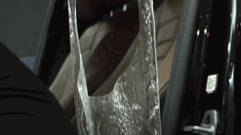 Clear PPF being stretched and positioned along the edge of a car door during installation. The paint protection film appears wet as it is aligned and pressed into place for full coverage and adhesion. This step helps protect high contact areas from scuffs and everyday wear.