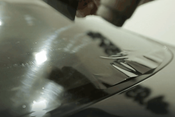 Close-up of window tint film being applied to a car window during professional automotive tint installation