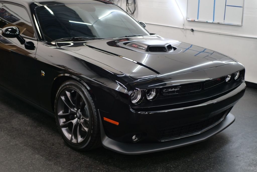 Black Dodge Challenger with professionally tinted windows inside the 48 Detailing shop.