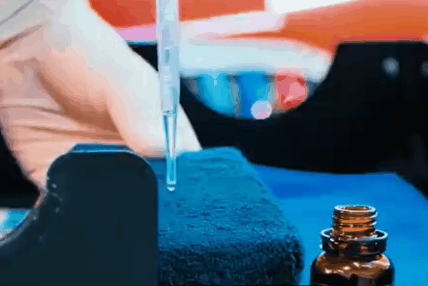 Close-up of ceramic coating liquid being applied to an applicator pad for vehicle paint protection.