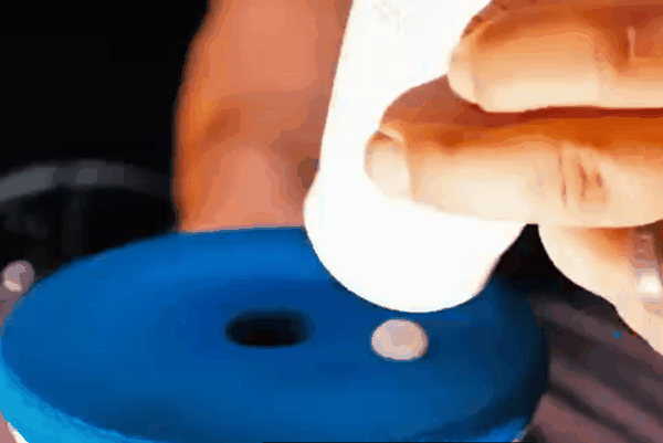 Ceramic coating product being applied to a blue applicator pad during vehicle paint protection prep.