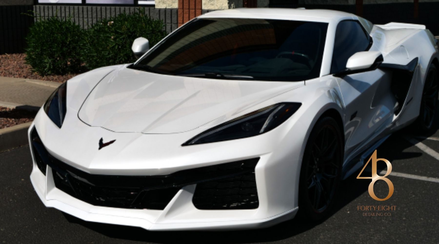 White Corvette C8 parked outdoors with 48 Detailing branding, showcasing its glossy exterior finish.