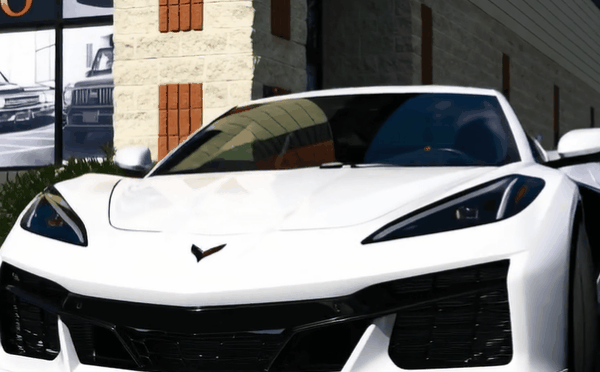 Front view of a white Corvette C8 outside 48 Detailing, highlighting its sharp body lines, headlights, and glossy paint finish.